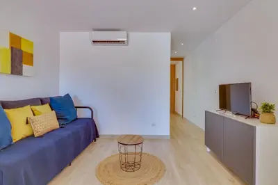 a living room with a blue couch and a tv at Side Villas - 1bdr Retreat with BBQ & Patio in Quarteira