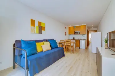 a living room with a blue couch and a kitchen at Side Villas - 1bdr Retreat with BBQ & Patio in Quarteira
