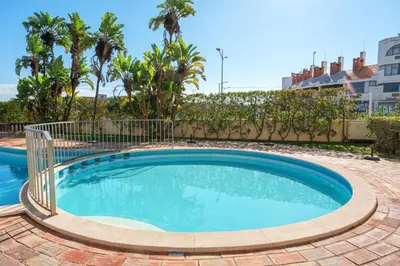 a swimming pool in front of a building with palm trees at BnB Homes Apartment with cozy Terrace & 2 Swimming pools near the heart city in Albufeira