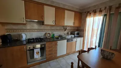 a kitchen with wooden cabinets and a table and a tableablish at Villa V3 - Vale Pedras in Albufeira