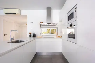 a white kitchen with white cabinets and a sink at Stylish 3-Bedroom Villa Haven with a Private Pool in Albufeira