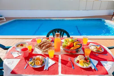 a table with plates of food and fruit next to a swimming pool at Villa Azzurra by Algarve Vacation in Albufeira
