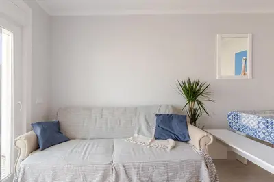 a white room with a bed with blue pillows at BrisaMar Villas: Sol, Mar, Serenidade in Albufeira