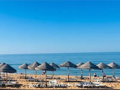 a group of umbrellas and chairs on a beach at BrisaMar Villas: Sol, Mar, Serenidade in Albufeira
