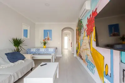 a living room with a white couch and a colorful wall at BrisaMar Villas: Sol, Mar, Serenidade in Albufeira