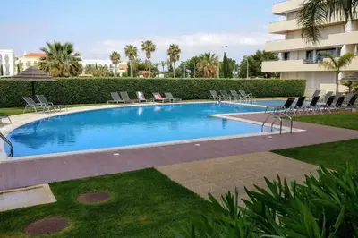 a large swimming pool with chairs and a building at VilamouraSun Aquamar Penthouse 601 in Quarteira