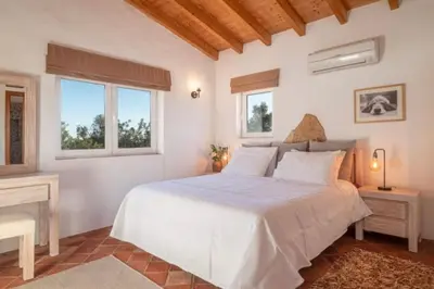 a white bedroom with a bed and two windows at Casa Grayson in Loulé