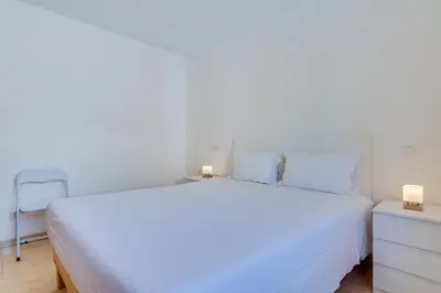 a white bed with two candles on a night stand at Apartamento Al Sakia 2bdr com piscina e ar condicionado in Quarteira