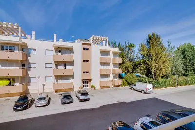 an apartment building with cars parked in a parking lot at Apartamento Al Sakia 2bdr com piscina e ar condicionado in Quarteira