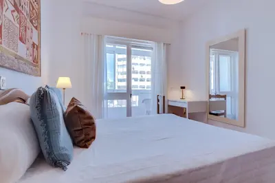 a white bedroom with a large bed and a window at Maresia 2 Bedroom Oceanfront Apartment in Quarteira in Quarteira