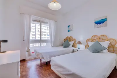 a white bedroom with two beds and a window at Maresia 2 Bedroom Oceanfront Apartment in Quarteira in Quarteira