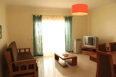 a living room with a tv and a chair and a table at Akisol Albufeira Aqua II in Albufeira
