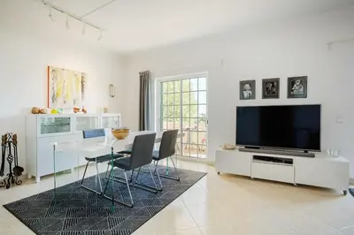 a white living room with a table and a television at Villa Nascente Balaia in Branqueira