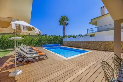 a deck with a pool and chairs and an umbrella at Villa Casa Joao by Villa Plus in Albufeira