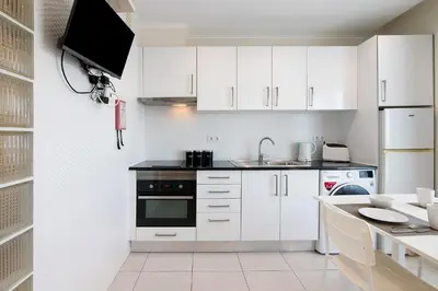 a kitchen with white cabinets and a washer and dryer at Bay View Albufeira in Albufeira
