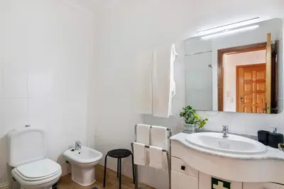 a white bathroom with a toilet and a sink at Cosy Apartment With Pool 2 in Vilamoura