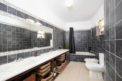 a bathroom with two sinks and a toilet and a tub at Villa Baltin in Albufeira