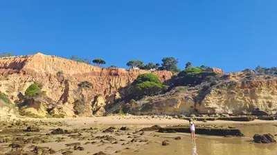 a person standing in the water on a beach at Praia da Falésia, O Melhor Estúdio da Aldeia das Acoteias in Albufeira
