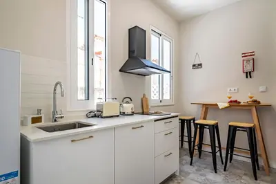 a kitchen with white cabinets and a sink and a table at Casas das Ilhas in Faro