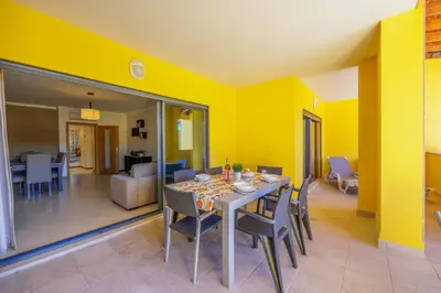a dining room with yellow walls and a table and chairs at Palm Breeze Terrace Vilamoura in Vilamoura