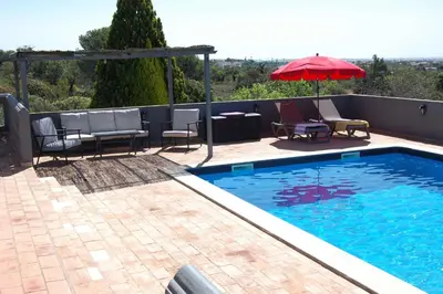 a swimming pool with chairs and a red umbrella at Holiday home in Santa Barbara de Nexe - Algarve 51807 in Santa Bárbara de Nexe