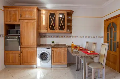 a kitchen with wooden cabinets and a table and a dishwasher at Villa Agadir by Algarve Vacation in Albufeira