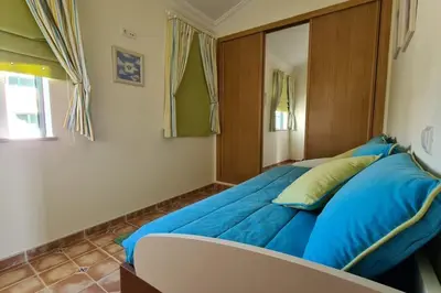 a bedroom with a blue bed with a wooden headboard at Vila Rafaella - Praia de São Rafael in Sesmarias