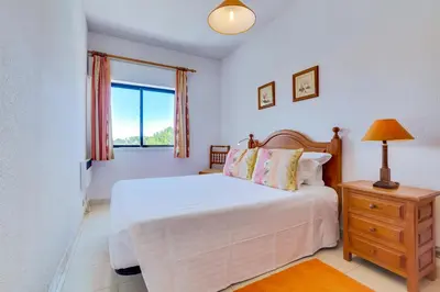 a bedroom with a bed and a dresser and a window at Apartamento Farol com piscina e estacionamento in Vilamoura
