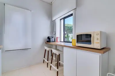 a kitchen with a counter with a microwave and a window at Apartamento Farol com piscina e estacionamento in Vilamoura