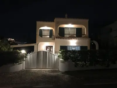a white house with a gate at night at 4 Bedroom Villa with Heated Pool close to Old Village in Vilamoura