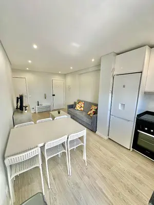 a kitchen and living room with a table and a couch at Julio Apartment in Albufeira
