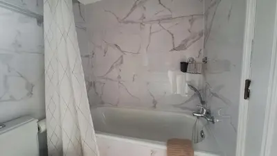 a bathroom with a white tub and a marble wall at Apartamento Olhos do Mar in Olhos de Água