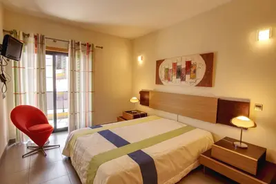 a bedroom with a bed and a red chair at Parque Atlântico Modern Seaview Apartment with Pool and Tennis Court in Cavacos