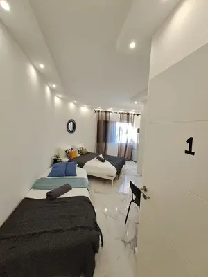two beds in a white room with a hallway at Albufeira flats in Albufeira