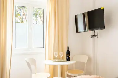 a living room with a table and a tv on a wall at Urban Bliss Guesthouse I in Faro