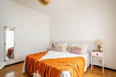 a white bedroom with a bed with an orange blanket at Urban Bliss Guesthouse I in Faro