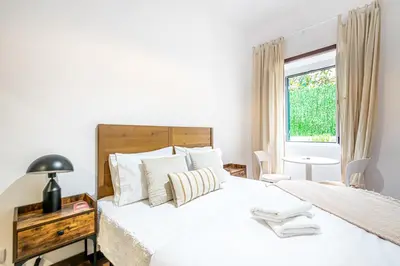 a white bedroom with a large bed and a window at Urban Bliss Guesthouse I in Faro