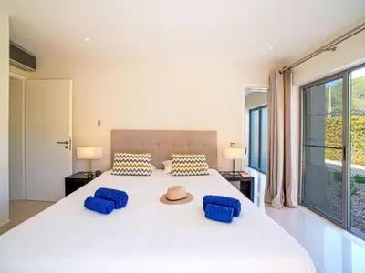 a bedroom with a large white bed with two blue pillows at Apartment Pine Hills Diamante-12 by Interhome in Vilamoura
