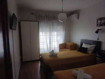 a bedroom with two beds and a chair and a window at Faro Stadium Flat by Freetimealgarve in Faro