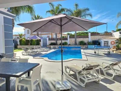 a dining table and chairs next to a swimming pool at Villa Jorge by Ecovillas Albufeira in Galé