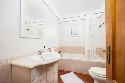 a bathroom with a sink and a toilet and a tub at Villa Amendoeira in Albufeira
