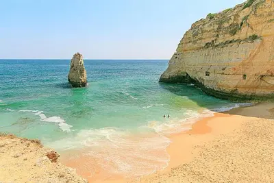 two people swimming in the ocean near a beach at Villa Amendoeira in Albufeira
