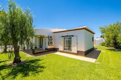 a small white house with a green yard at Villa Amendoeira in Albufeira