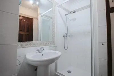 a white bathroom with a sink and a shower at Old Village- 2A Village Street in Quarteira