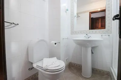 a white bathroom with a toilet and a sink at Old Village- 2A Village Street in Quarteira