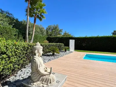 a statue of a buddha sitting next to a pool at Stunning 4-Bedroom Villa With Pool - Perfect For Families in Albufeira