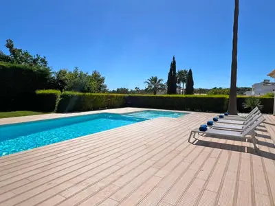 a swimming pool with two chairs and a palm tree at Stunning 4-Bedroom Villa With Pool - Perfect For Families in Albufeira