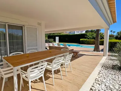a patio with a wooden table and chairs at Stunning 4-Bedroom Villa With Pool - Perfect For Families in Albufeira