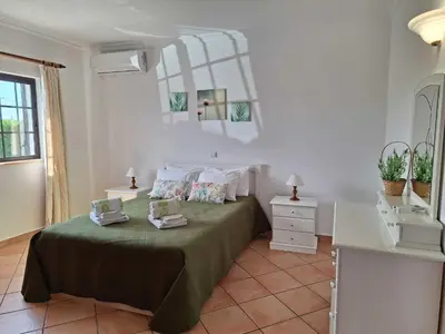 a bedroom with a green bed with a mirror at Villa Ramos by Ecovillas Albufeira in Roja- Pé