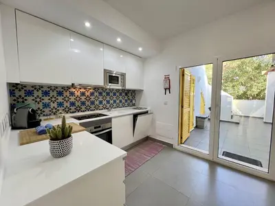a kitchen with white cabinets and a large window at Vilamoura Club Villa 1 With Pool by Homing in Vilamoura
